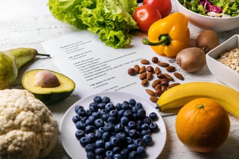 A collection of colorful berries, fruits, vegetables, and almonds on top of a white piece of paper featuring a daily mealplan.