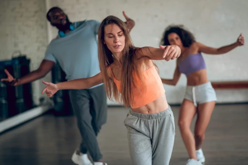 A female dance teacher teaches choreography to two students during class.