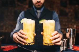 A bartender holding two drinks.