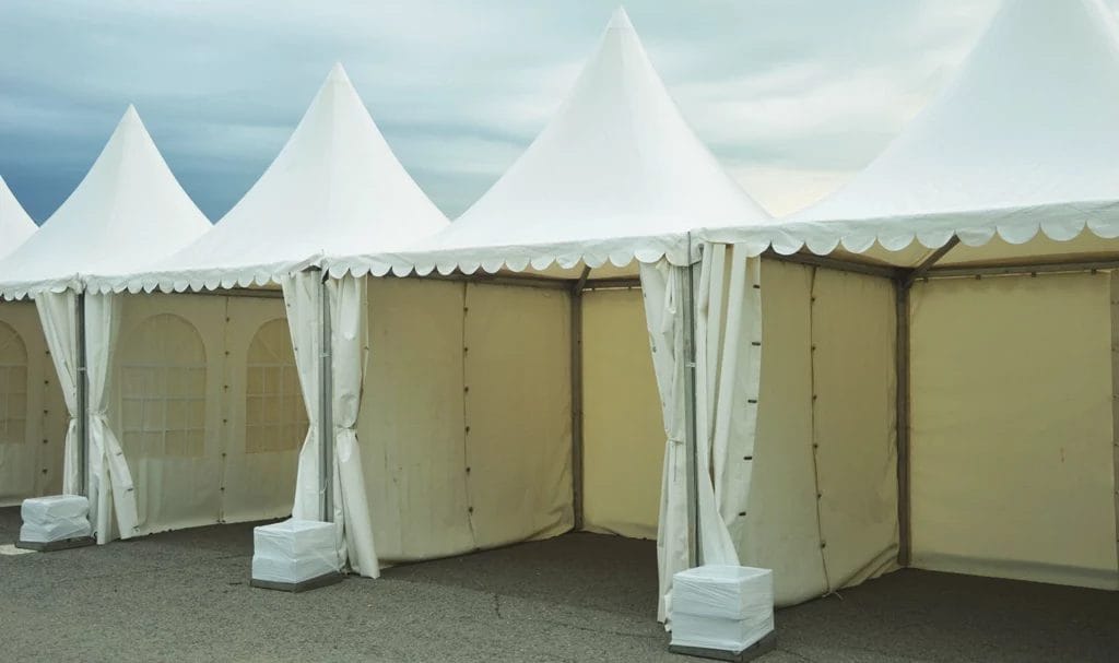 A row of empty vendor booth tents outside with weights to keep them steady.