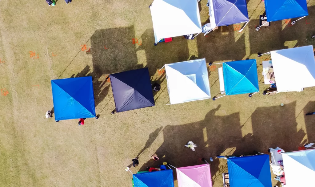 Arial shot of vendor booth tents on grass at an outdoor event.