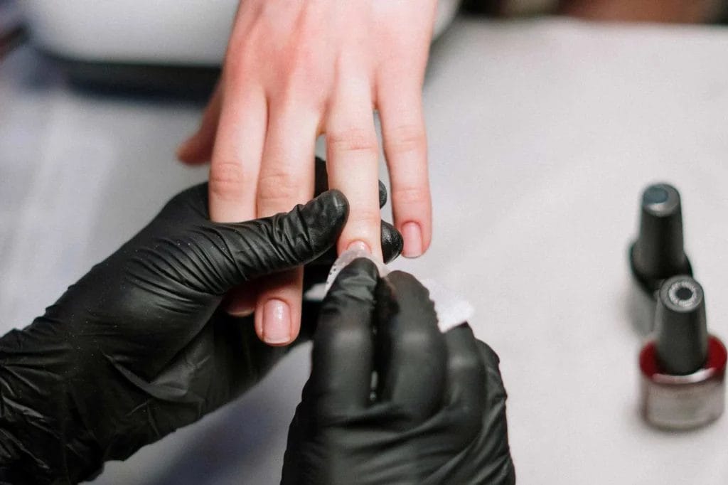 Close-up of a nail tech prepping a client's nail beds for painting