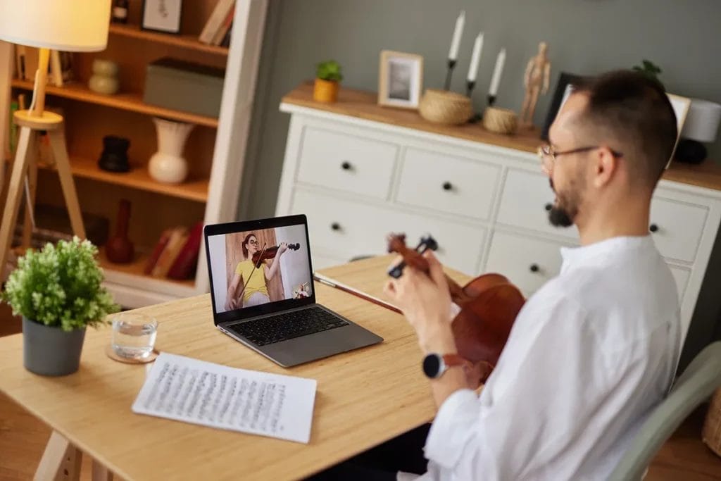 A man learns how to play the violin in an online lesson.