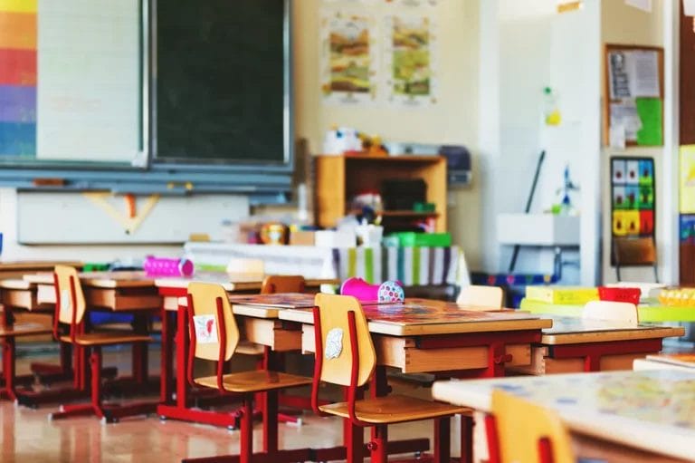 Empty desks in a well-decorated classroom lit with natural light.