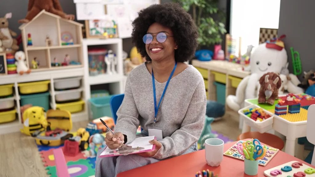 Smiling teacher with clipboard in classroom for young children