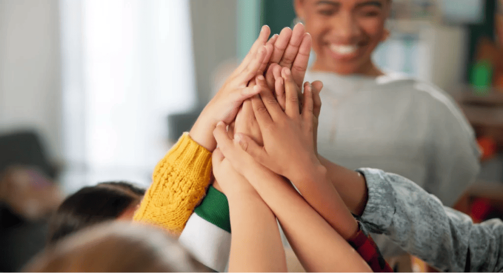 Teacher and group of students give high fives.