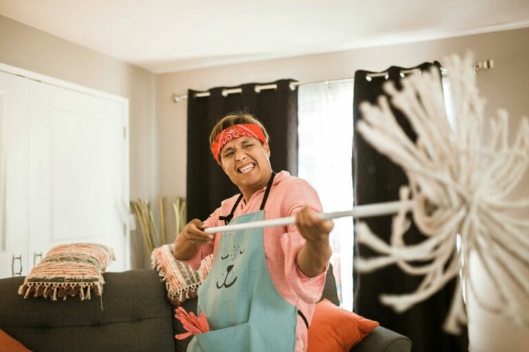 a smiling man holds out a mop