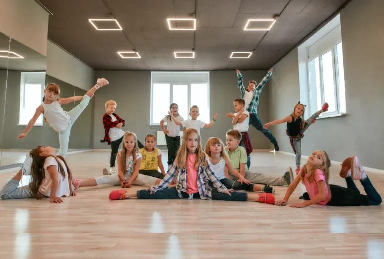 A group of kids in a dance all hit different dance poses for a photo in a new studio space.