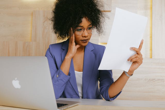 a woman in professional attire looking at a piece of paper