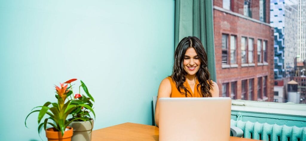 Woman against blue background at her computer