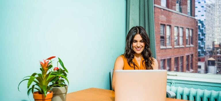 Woman against blue background at her computer