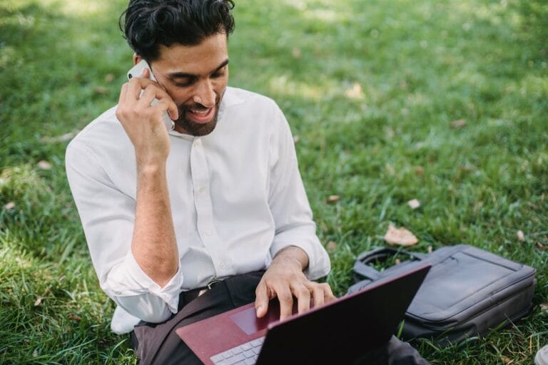 A Businessman Having a Phone Call while Using His Laptop