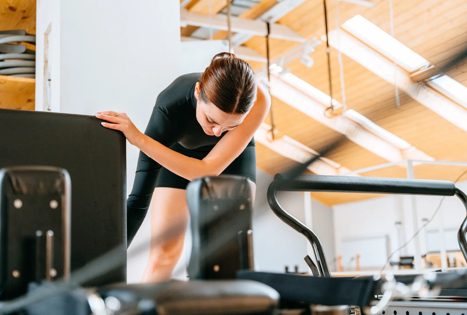 An instructor adjusts the resistance on a Pilates Reformer machine.