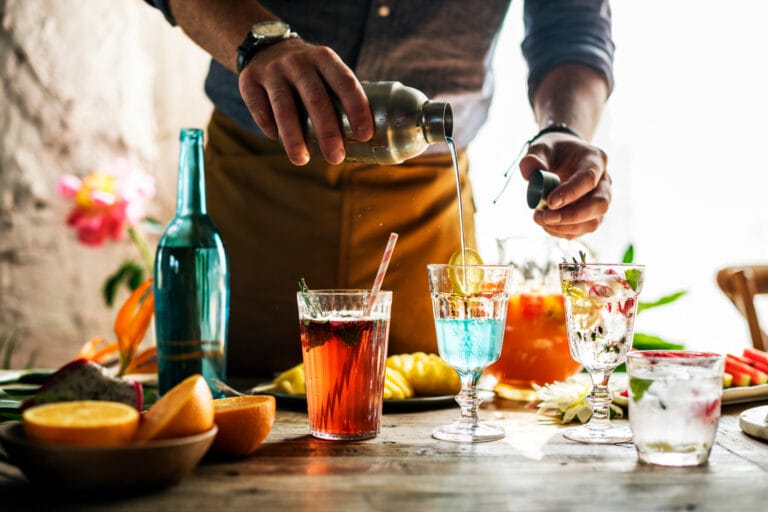 Bartender pouring drinks into various glasses at an event.