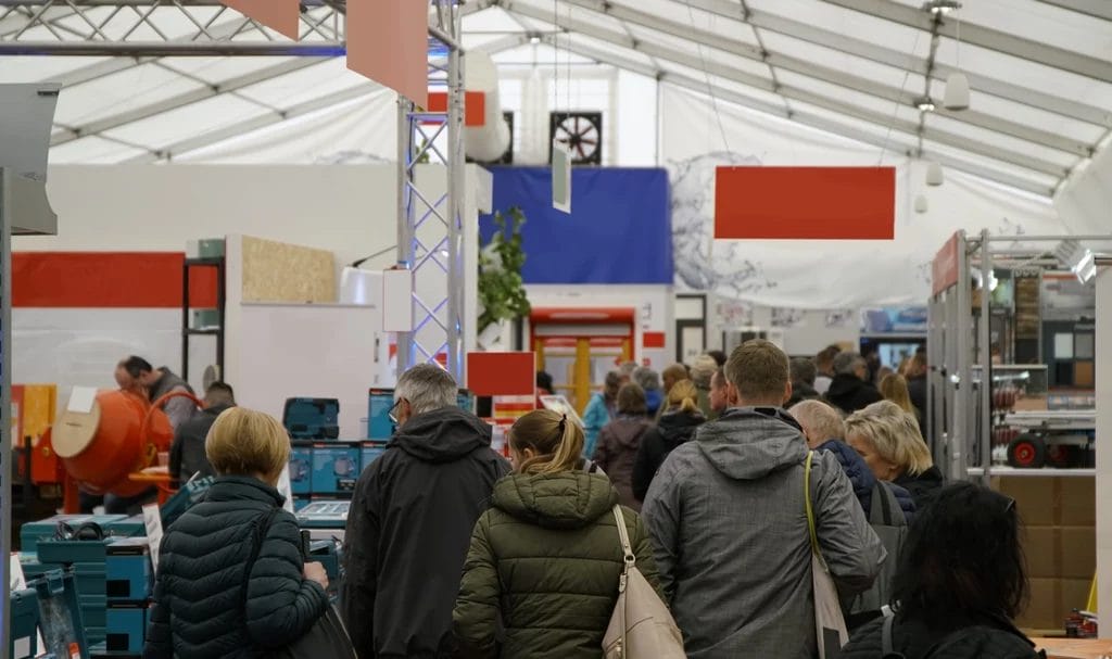 A crowd of people walking down the busy walkways of an expo.
