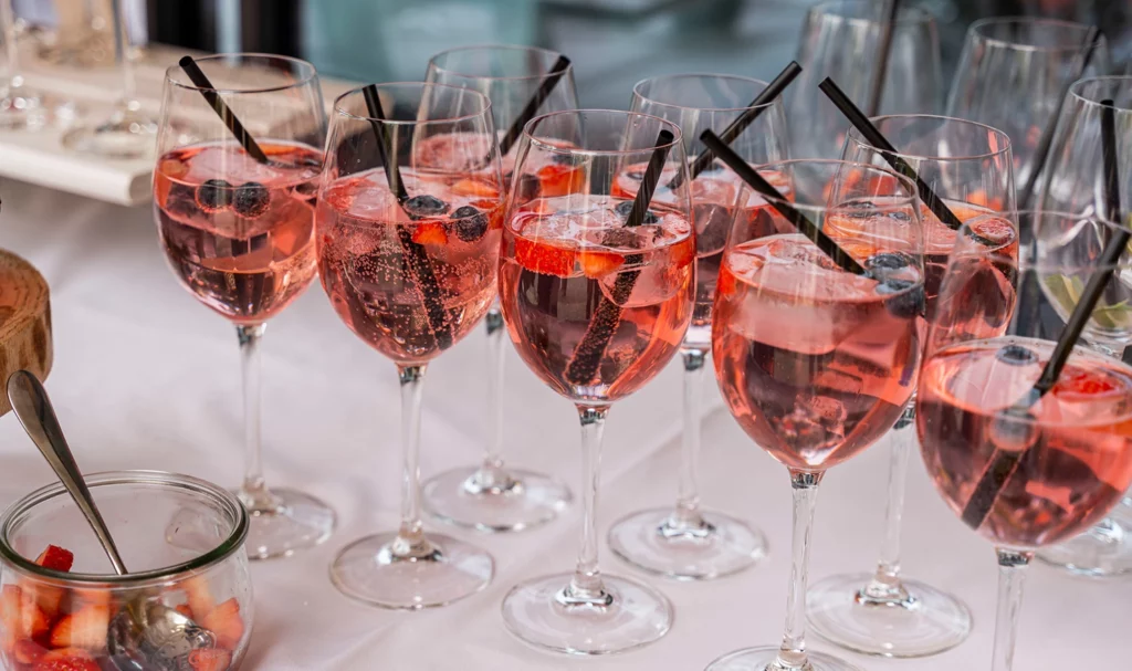 Glasses of a berry sparkling wine drink in champagne glasses on a buffet at a wedding party.