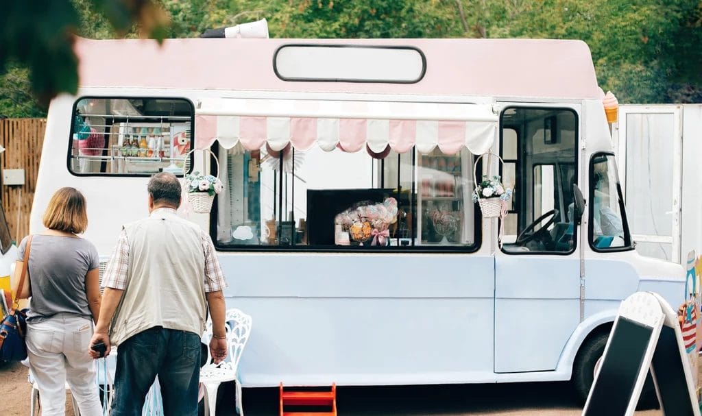 A stylish retro food truck is serving customers at summer street food festival.