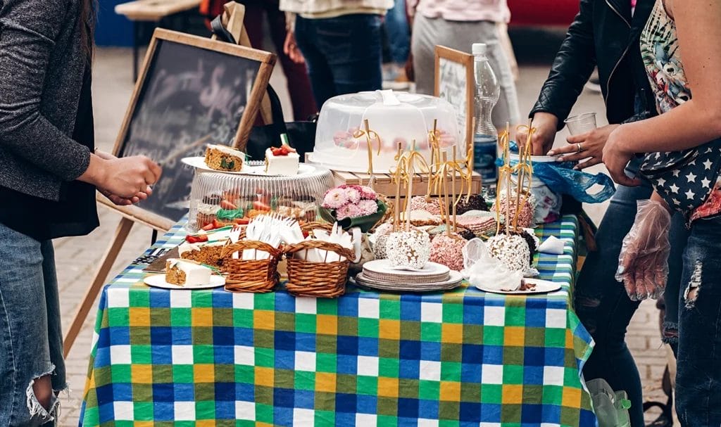 Colorful desserts and cookies on a table with a checkerboard tablecloth at a street food festival.