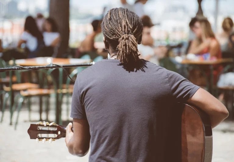 A musician at a local cafe with local bystanders who wants to use photos of this gig to market himself.