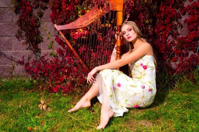 A harpist sitting outdoors with her harp.