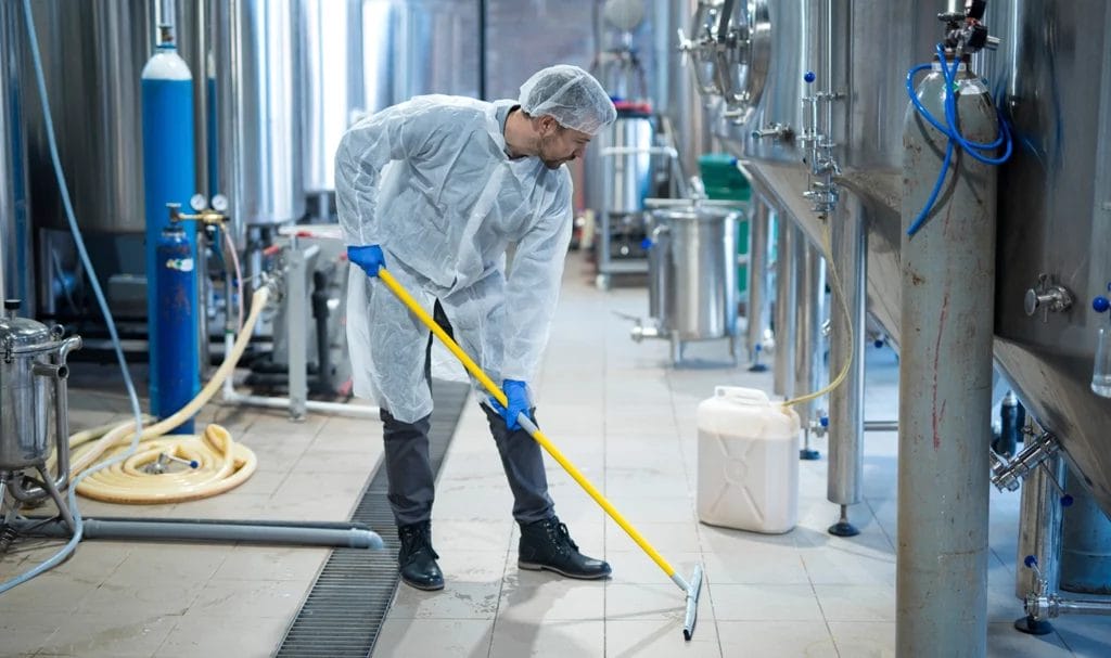 A professional industrial cleaner in a protective uniform deep cleaning the floors.