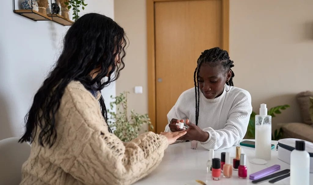 A beautician is painting the nails of a customer in a home salon.