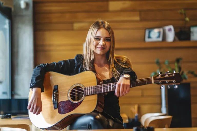 Woman musician sitting in a cafe with a guitar.