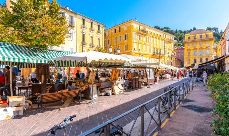 Outdoor art market in a city center full of vendors with open air booths selling paints, handmade crafts, original art, and more.