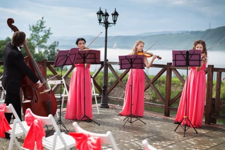String musicians playing at an outdoor wedding ceremony.