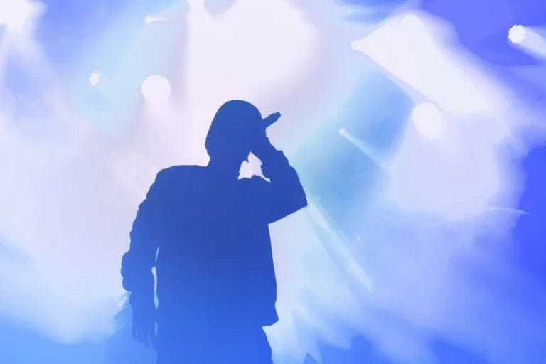 A silhouette of a rapper on stage spitting hot bars.