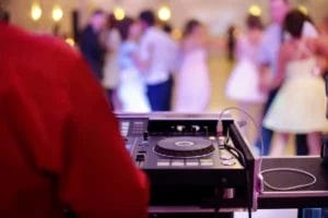 A wedding DJ with equipment at a wedding reception.