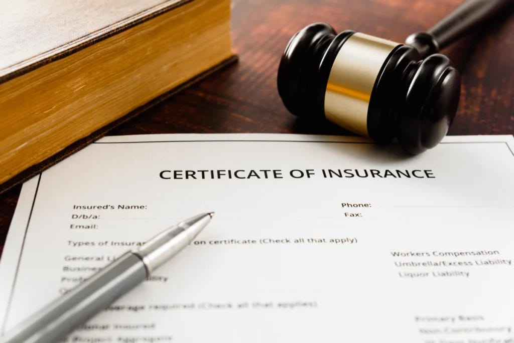 Certificate of insurance form on a desk with a pen and a gavel.