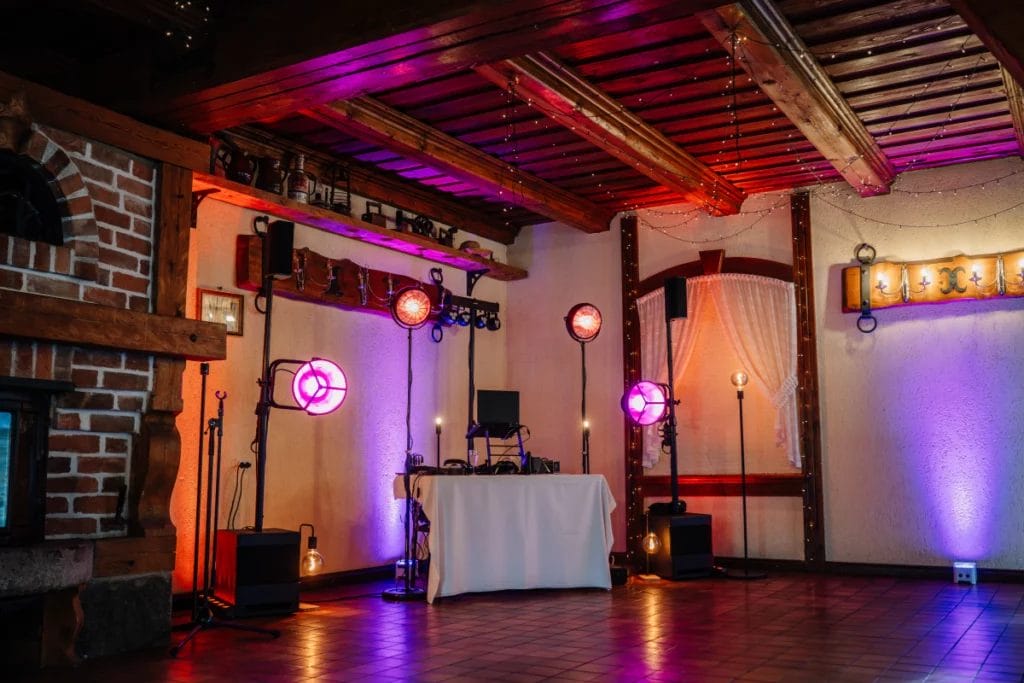 DJ booth on the dance floor for a rustic wedding with red and violet lights.