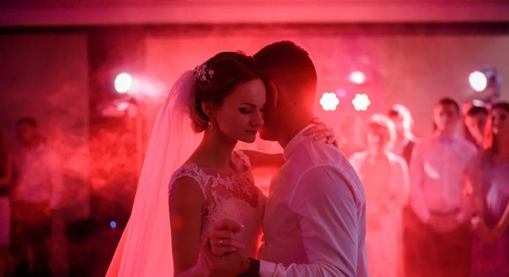 A close up of a bride and groom during their first dance with red lights and a red background.
