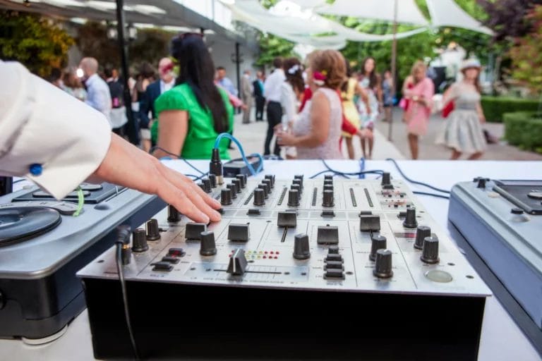 A wedding DJ spinning at an outdoor ceremony.