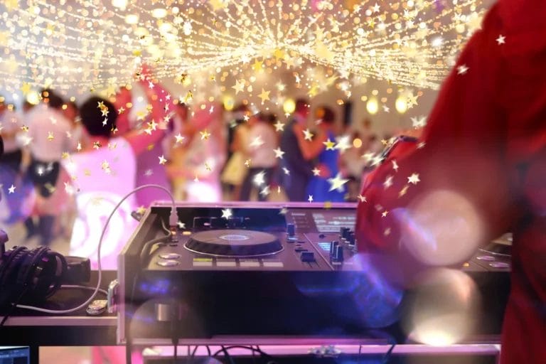 A wedding DJ spinning at a ceremony with glitter decorations.