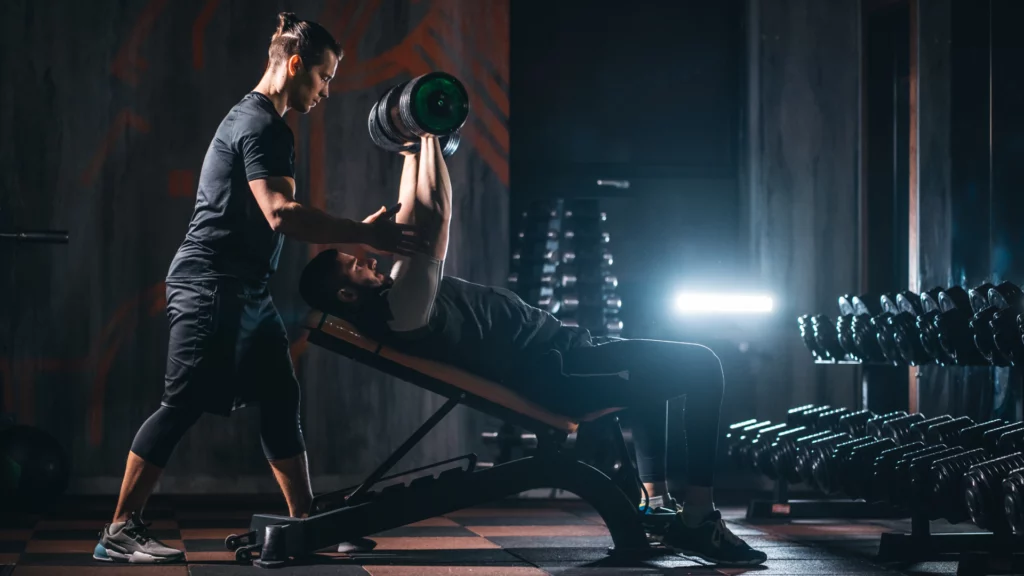 Personal trainer spotting client while they bench press in the gym