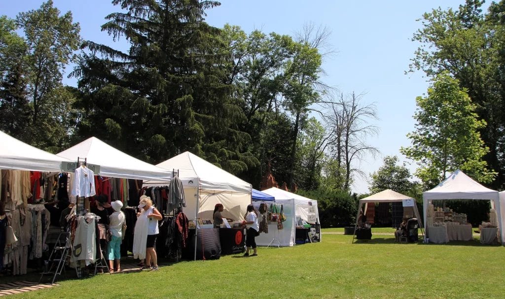 Outdoor art festival with popup vendor tents selling products to customers.