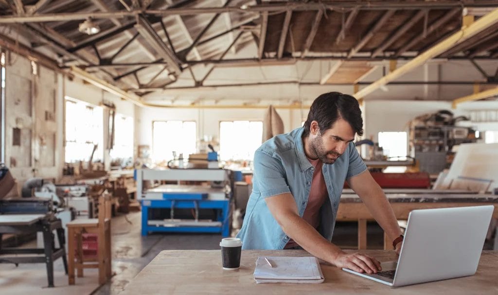 Woodworker using a laptop in his workshop.