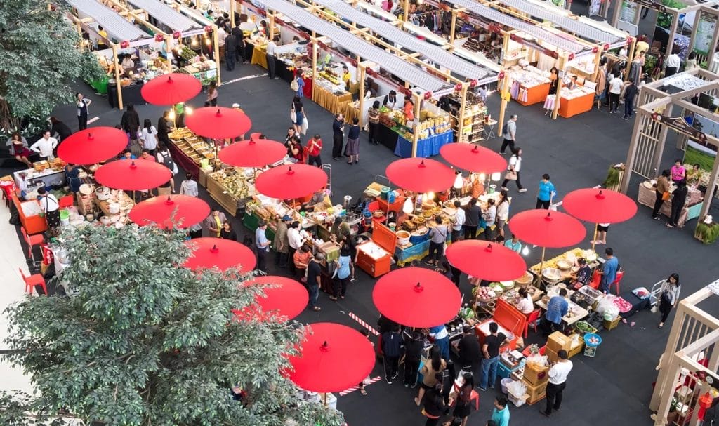 A bird-eye view of an outdoor market where food vendors and product sellers are interacting with customers.
