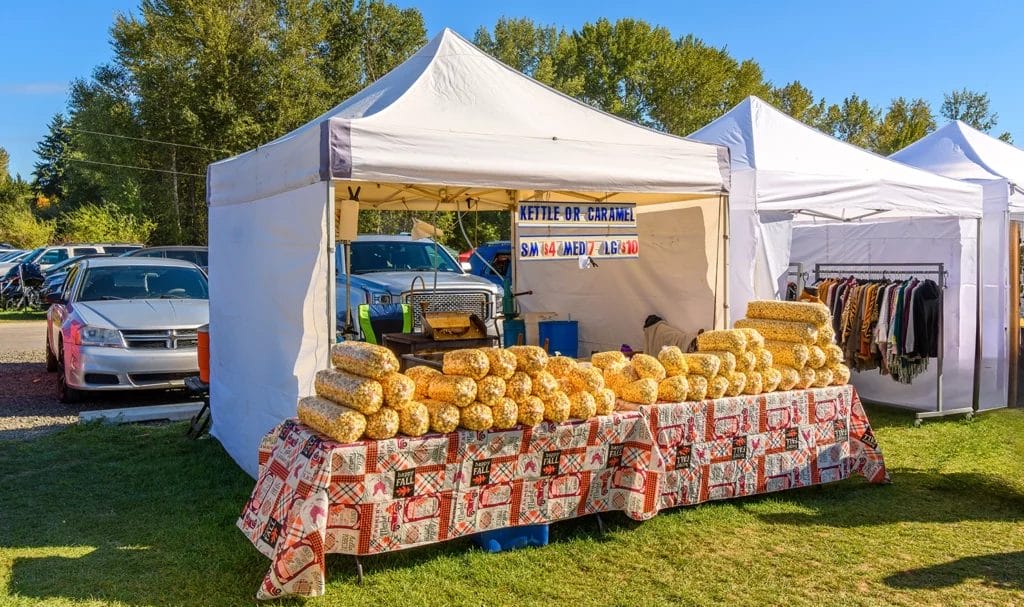 A popcorn vendor is setup and ready to sell bags of fresh popcorn at an outdoor event.