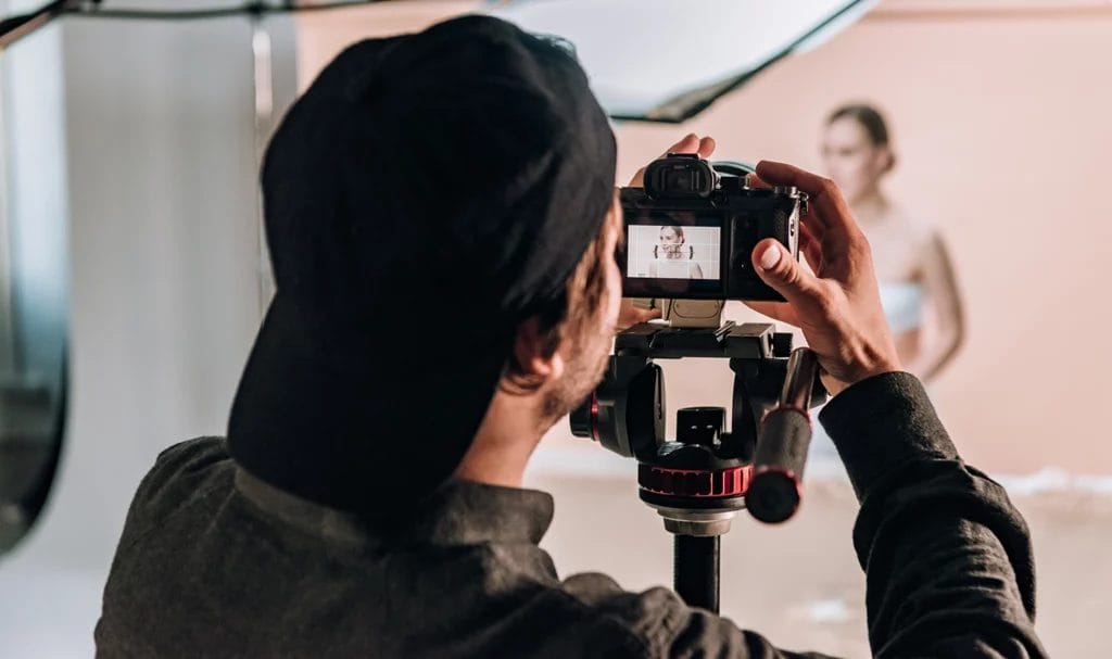 A behind-the-scenes look at a photographer adjusting the settings on his camera during a photoshoot in a rented studio.