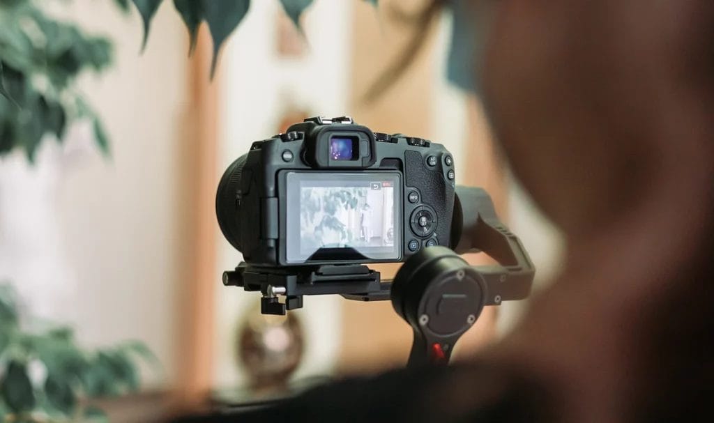 Zoomed in look at a videographer recording with a mirrorless camera and gimbal.