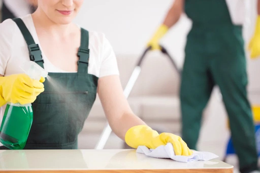 A woman spraying a table with disinfectant.
