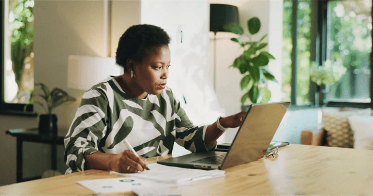 Serious businesswoman wearing a boldly printed top works from home on a laptop
