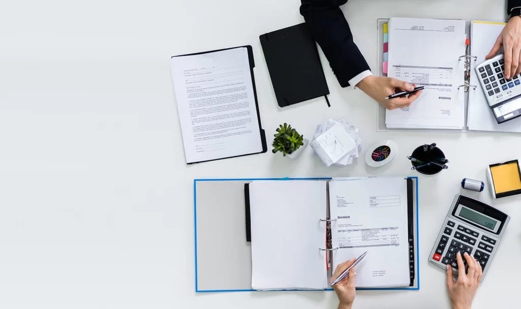 Two business owners calculating expenses on a white desk top.
