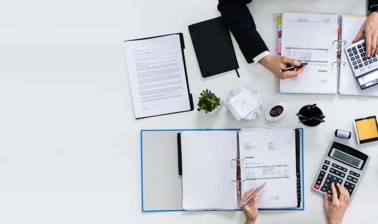 Two business owners calculating expenses on a white desk top.