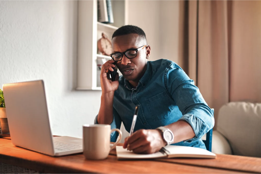 Serious, focused entrepreneur taking notes while talking on the phone