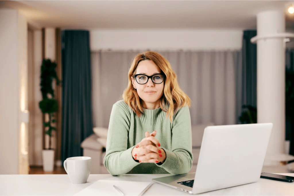 Calm, confident businesswoman working from home looks straight into the camera with hands folded