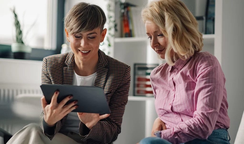 Two businesswomen sharing ideas using digital tablet.